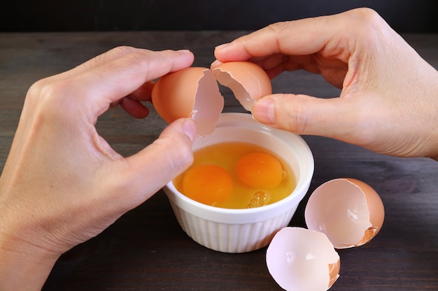 Las manos del hombre de primer plano romper el huevo en un recipiente