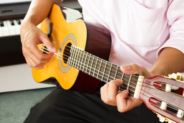 Las manos del hombre del primer que tocan la guitarra clásica.