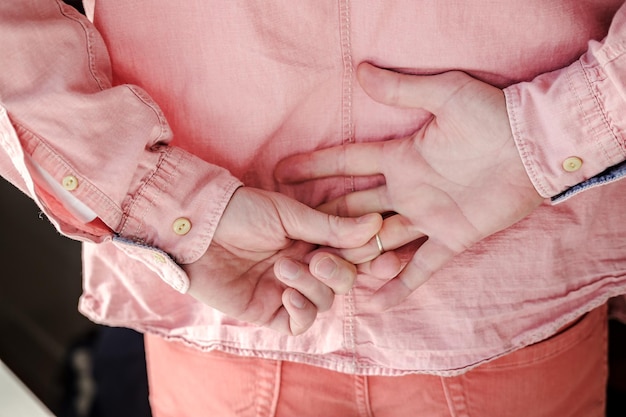 Foto manos de un hombre que quita el anillo de bodas de oro detrás de la espalda para ocultar su estado civil de la amante