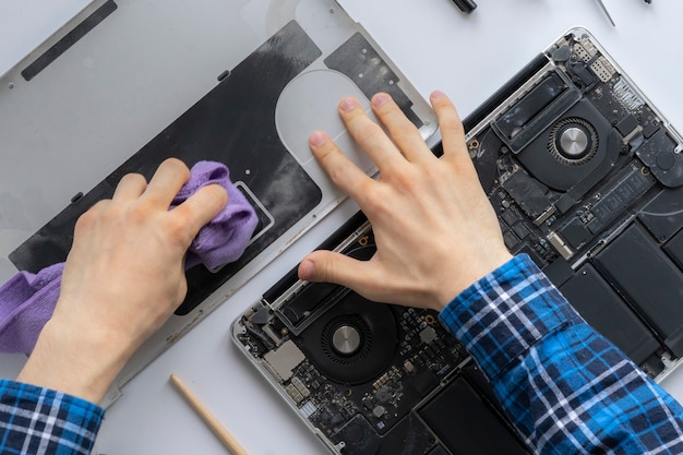 Foto las manos de un hombre que trabaja en el servicio informático y quitar el polvo de la computadora portátil personal