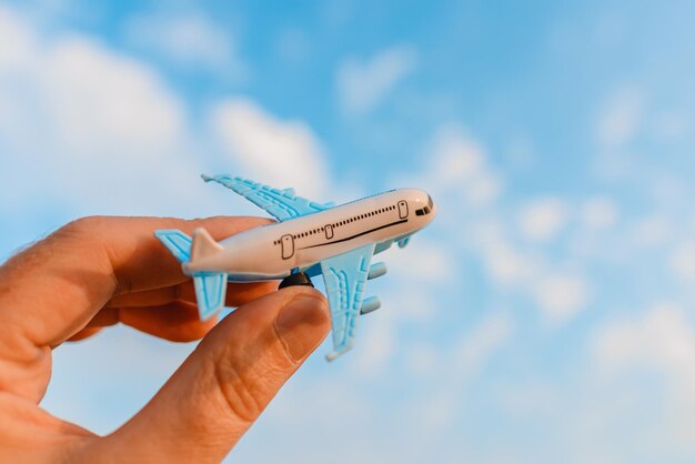 Manos de hombre sosteniendo un avión de juguete y tienen sueños quiere ser un piloto en un fondo nubes borrosas cielo azul sol