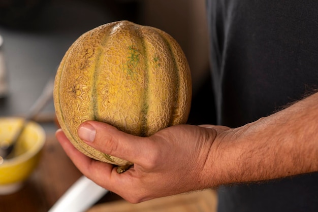 manos del hombre sosteniendo un melón