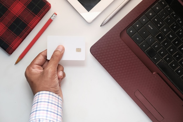 Manos de hombre sosteniendo tarjeta de crédito y usando el teclado para compras en línea