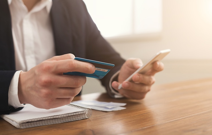Foto manos del hombre sosteniendo una tarjeta de crédito y usando un teléfono inteligente para compras en línea. pago en línea, espacio de copia