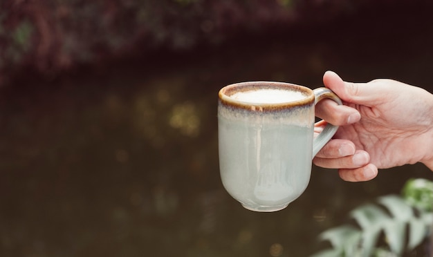 Manos de un hombre sosteniendo una taza de café con leche caliente