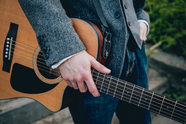 Las manos del hombre tocando la guitarra acústica