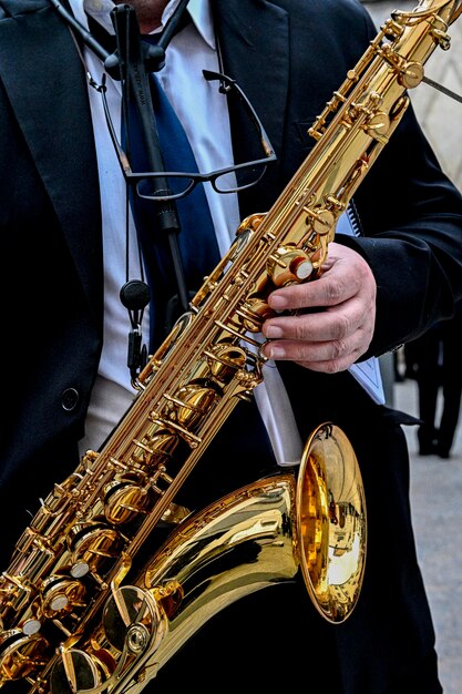 Manos de hombre tocando el saxofón en la orquesta.