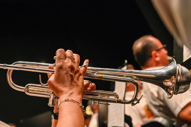 Manos de hombre tocando una trompeta en la orquesta.