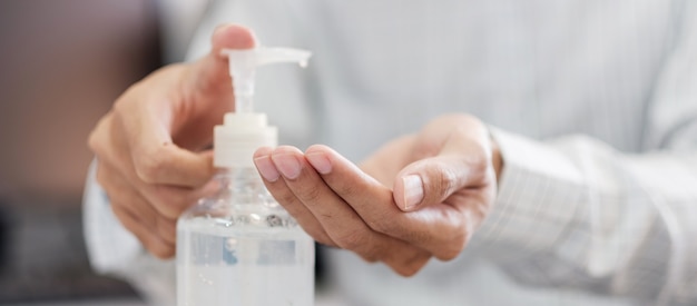 Manos de hombre usando gel de alcohol de lavado de manos o dispensador de botella de desinfectante