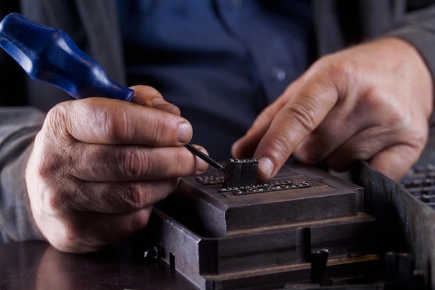 Las manos de los hombres crean una placa metálica