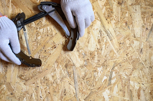 Las manos de los hombres enguantadas tienen freno de tambor de automóvil desmontado sobre una hoja de fondo de madera contrachapada de osb. endecha plana, vista superior. espacio para texto