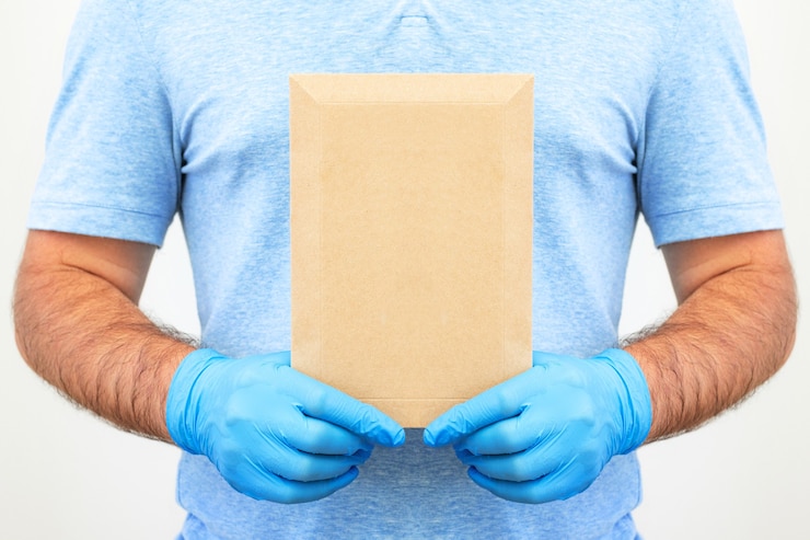 Las manos de los hombres en guantes médicos sostienen un sobre con documentos. Servicio de entrega. Servicio Postal.
