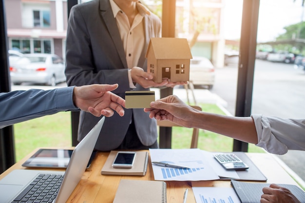 Las manos de los hombres que están entregando tarjetas de crédito a los clientes, el concepto de préstamo hipotecario con c