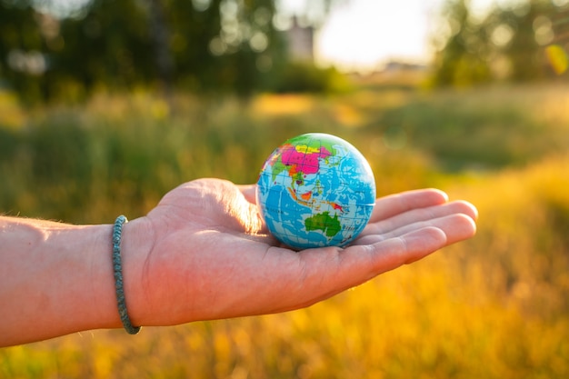 Foto las manos de los hombres sostienen un globo al atardecer en el parque el concepto de protección del medio ambiente