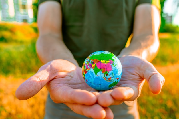 Las manos de los hombres sostienen un globo al atardecer en el parque El concepto de protección del medio ambiente