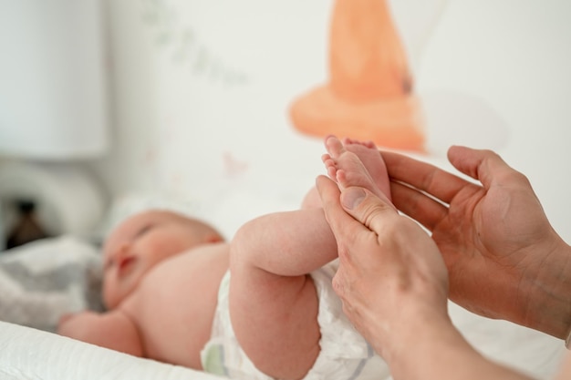 Las manos de los hombres sostienen las piernas pequeñas de un bebé recién nacido