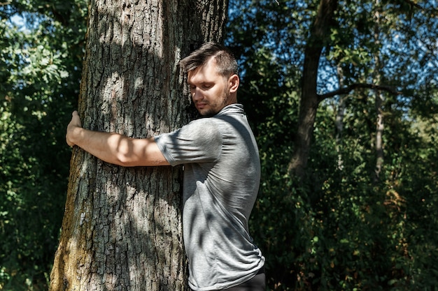 Las manos humanas se abrazan, envuelven un árbol.