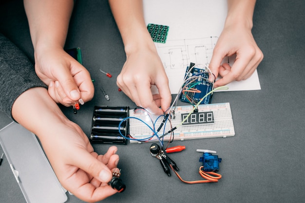 Manos de ingenieros que conectan componentes electrónicos.