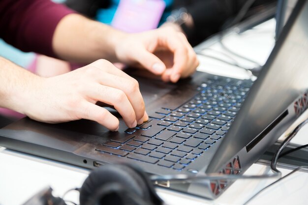 Manos de irreconocible joven recortada escribiendo en la computadora portátil.