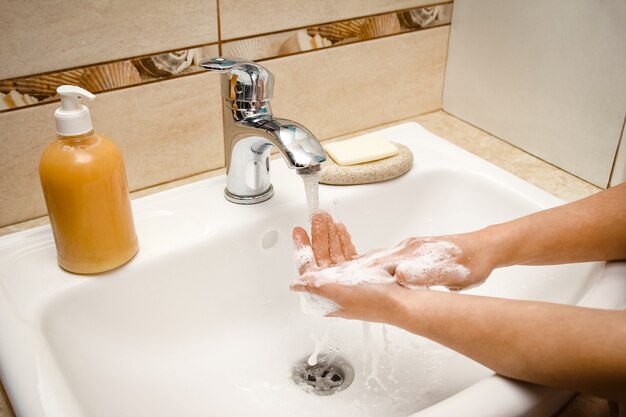 Las manos con jabón se lavan bajo el grifo con agua. Limpiar de infecciones, suciedad y virus.