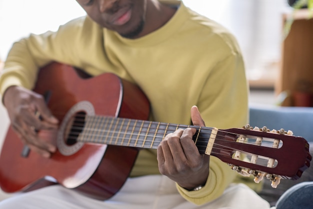 Manos del joven africano tocando la guitarra delante de la cámara