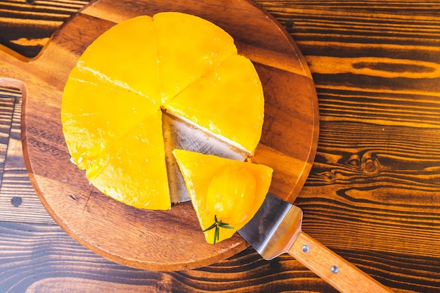 Manos de un joven chef panadero cortando una rebanada de tarta de queso con mango