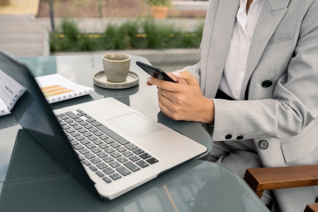 Manos del joven corredor mujer elegante enviando mensajes de texto a través del teclado de la computadora portátil