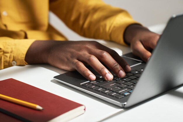 Manos de un joven empresario solitario presionando los botones del teclado de la computadora portátil