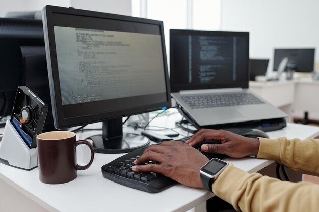 Manos de un joven programador o un ingeniero que decodifica datos en la pantalla de la computadora