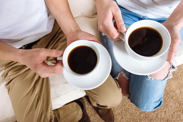 Manos de jóvenes amantes sosteniendo una taza de café