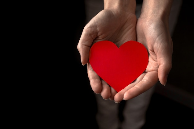 Manos jóvenes con corazón rojo. Ofreciendo ayuda y concepto de amor. Foto de fondo del día mundial de la salud y la salud mental