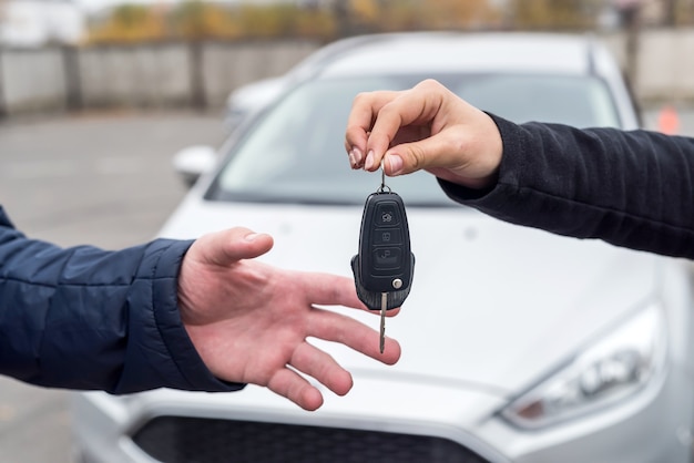 Manos con llaves contra coche nuevo de cerca