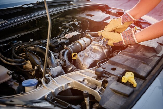 Manos con llaves y motor de coche de cerca. Concepto de servicio de coche