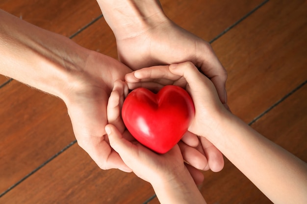 Manos de la madre y el niño con corazón rojo en madera