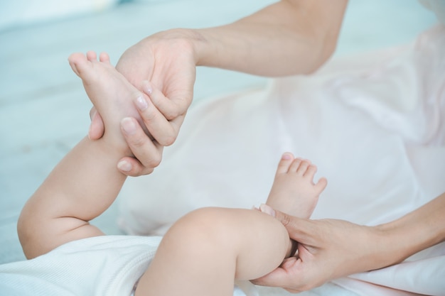 Manos de la madre sosteniendo los pies del bebé en la habitación.