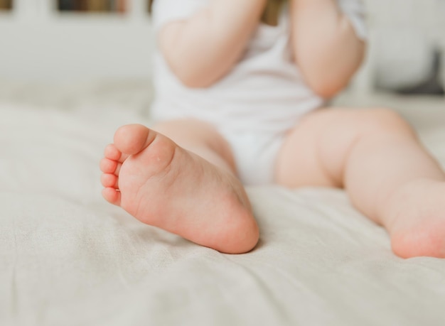 Las manos de la madre sostienen las piernas del bebé en una cama de algodón higiene y cuidado y cuidado del talón del recién nacido