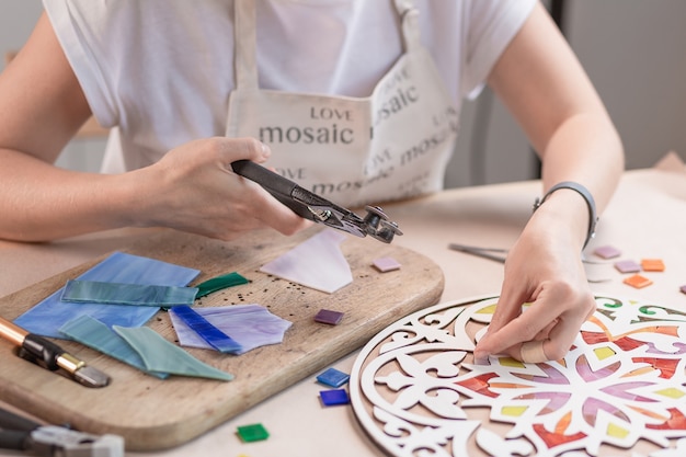 Manos del maestro trabajando en nuevo mosaico colorido moderno. De cerca