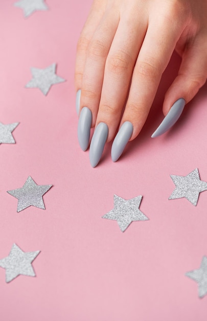 Manos con manicura gris sobre un fondo rosado