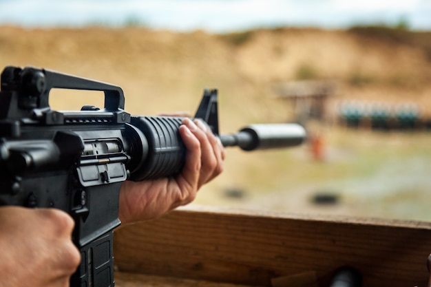 Las manos mantienen un rifle automático en el tablero del tirador.