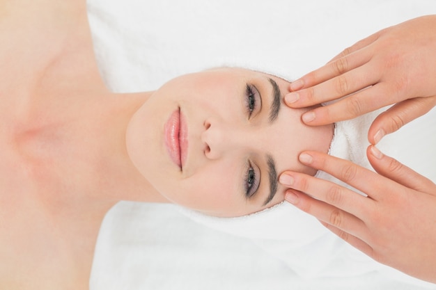 Manos masajeando la frente de mujer en el spa de belleza