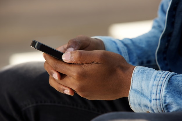 Manos masculinas africanas sosteniendo teléfono móvil