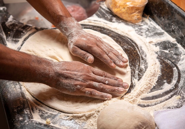 Foto las manos masculinas amasan la masa en la mesa con la harina en primer plano de las manos