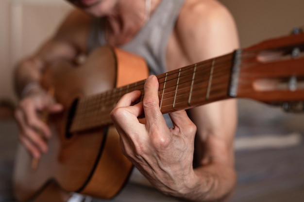 Manos masculinas de un anciano caucásico sosteniendo y tocando una guitarra clásica de cerca en casa guitarrista sin rostro no profesional la gente toca música amateur pasatiempos domésticos y ocio