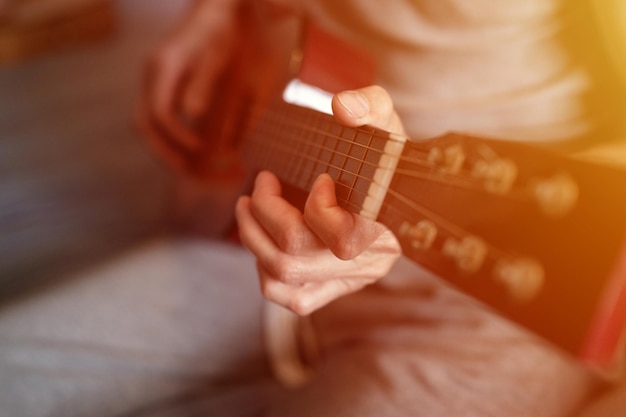 Manos masculinas de un anciano caucásico sosteniendo y tocando una guitarra clásica de cerca en casa guitarrista sin rostro no profesional la gente toca música amateur pasatiempos domésticos y ocio