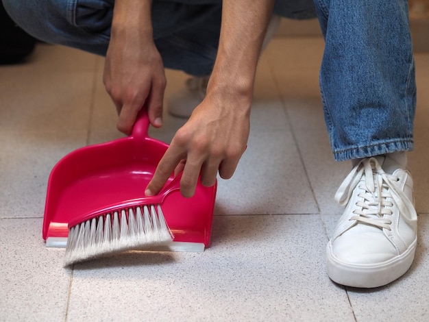 Manos masculinas barriendo el suelo