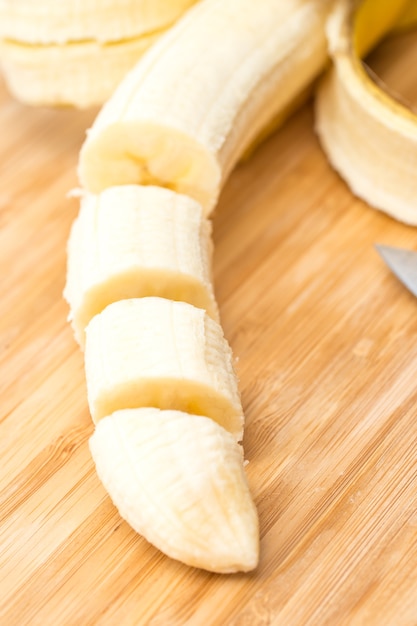 Foto manos masculinas cortando plátano en el tablero de la cocina. de cerca. enfoque selectivo.