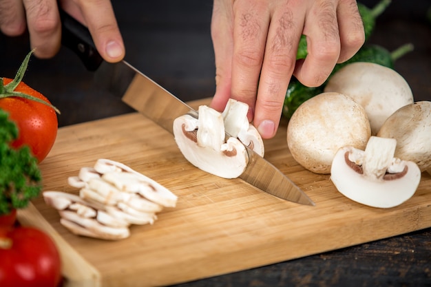 Manos masculinas cortando verduras para ensalada