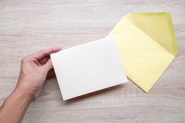 Manos masculinas escribiendo tarjetas vacías en la mesa de madera.