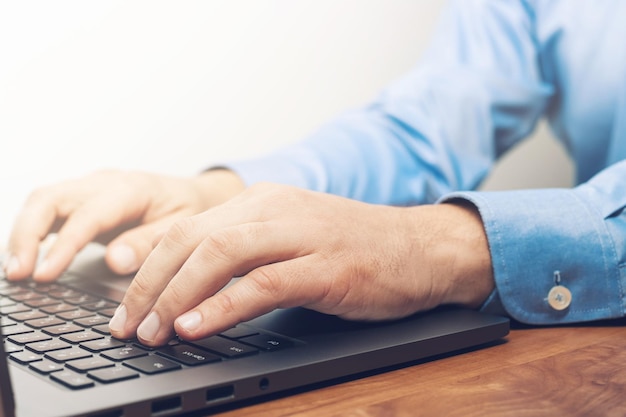 Manos masculinas escribiendo en un teclado de computadora portátil, vista cercana