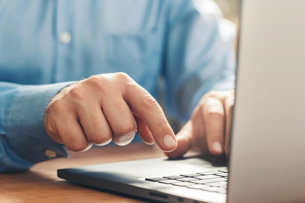 Manos masculinas escribiendo en un teclado de computadora portátil, vista cercana